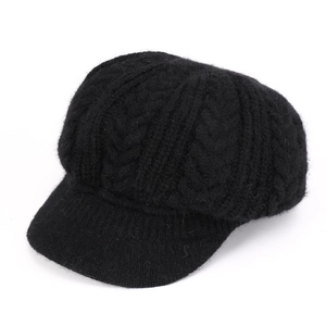 Detalle de gorro de punto trenzado negro con visera y textura de lana gruesa