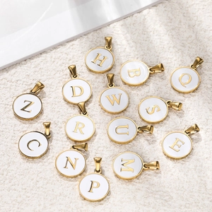 Flat lay detail of round gold stainless steel enamel letter charms on textured background