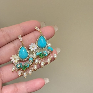 Detailed macro view of vintage turquoise earrings with white flowers and pearl tassels