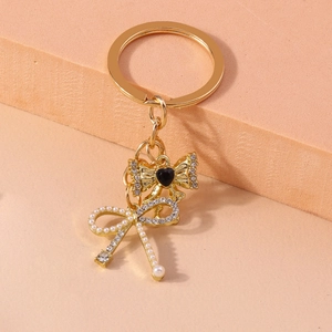 Detail of gold keychain with pearl and rhinestone bowknot charms and black heart gem