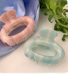 Detail of pink and blue acetate hair claws with marble texture and handmade gold lettering