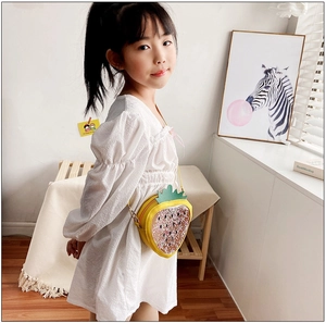 Little girl wearing a cute yellow strawberry crossbody bag with liquid glitter in a bright room