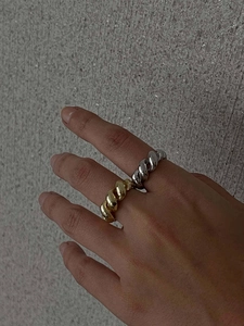 Detailed close-up of a two-tone 18K gold and silver twisted ring with polished metal texture