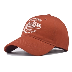 Detailed view of white vintage embroidery on a reddish-brown cotton baseball cap