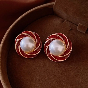 Detail of red enamel swirl earrings with large pearls on a luxury velvet jewelry box