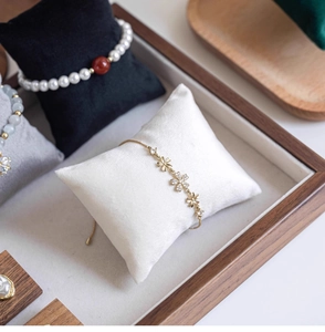 Detail of a gold flower bracelet with zircon inlay on a velvet display pillow
