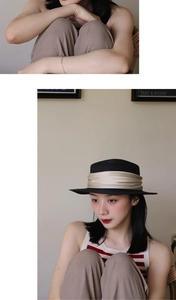 Detail of a black flat-top straw hat with champagne silk ribbon and elegant pleated design