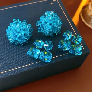Detailed close-up of blue crystal stud earrings set on a textured jewelry gift box
