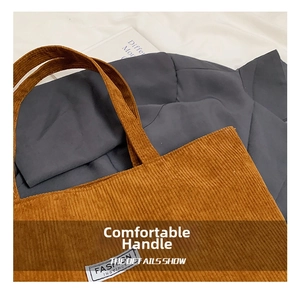 Detailed close-up of the textured brown corduroy tote bag and durable stitched handle