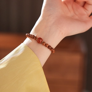 Close-up of red agate beaded bracelet with gold accents on a woman's wrist