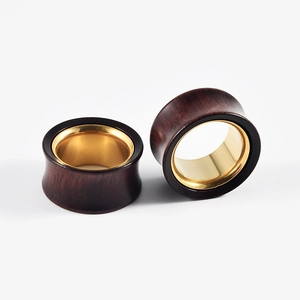 Close-up of wooden ear gauges with gold metal inner ring on white background
