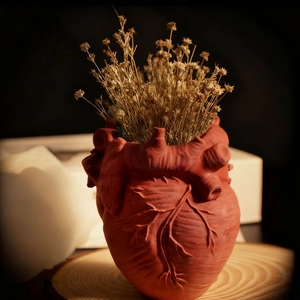 Anatomical heart shaped resin vase with rustic red finish and dried flowers decoration