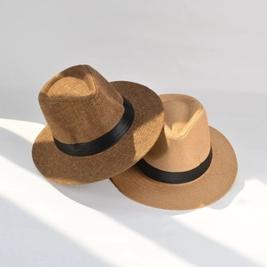 Close-up of textured straw Panama hats in brown and yellow with black ribbon detail