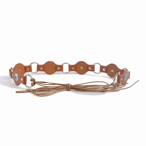 Detail of bohemian brown leather belt with turquoise studs and silver metal rings