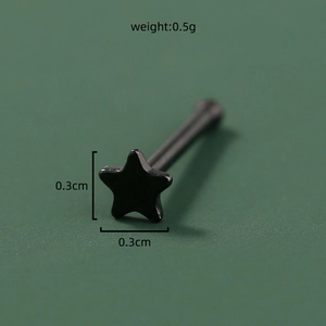 Macro view of a 0.3cm black star-shaped stainless steel nose stud on a green background