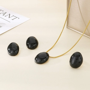 Detail of elegant gold snake chain necklace and black oval enamel pendant set