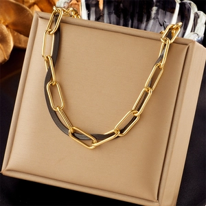 Close-up of dual-tone gold and black layered metal chain necklace on a leather stand