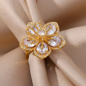Sparkling gold flower ring with cubic zirconia stones on an elegant beige silk background