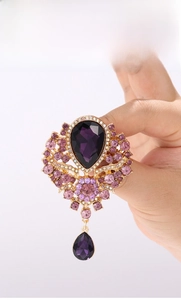 Detailed view of a vintage gold brooch with purple teardrop crystals and sparkling rhinestones