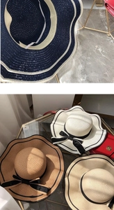 Detail of woven straw hats with wavy brims and black bow ribbons in multiple colors