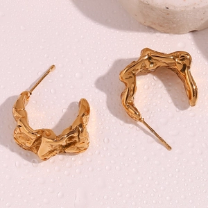 Detailed close-up of gold moon earrings with irregular lava texture and metallic finish