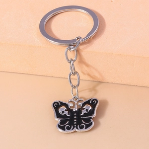 Detail of gothic butterfly keychain with white skull patterns on black enamel wings