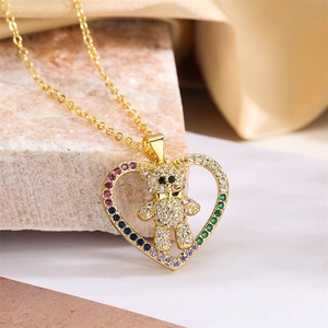 Detailaufnahme einer goldenen Herzkette mit einem kristallbesetzten Teddybären