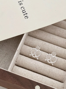 Detailed view of silver twisted heart stud earrings on a velvet jewelry display tray