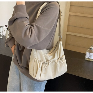Detailed view of beige nylon crossbody bag featuring ruched drawstring design and metal zipper