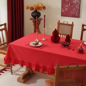 Close-up of red linen blend tablecloth featuring elegant ruffle edges on a wooden table