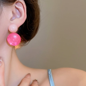 Close-up of model wearing pink resin round bead drop earrings with silver needle