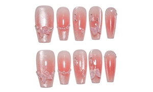 Detail of pink cat-eye press-on nails with 3D butterfly and pearl accents