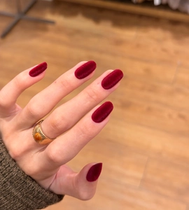 Macro detail of wine red velvet press-on nails with vintage gold gemstone ring