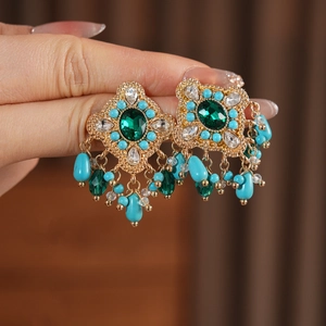 Vue détaillée de boucles d'oreilles vintage dorées avec pierre verte et perles bleues
