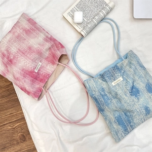 Detail of pink and blue tie-dye canvas tote bags with ethnic lace embroidery textures