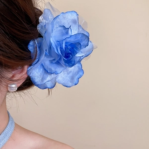 Détail d'une grande pince à cheveux en fleur de tissu bleu sur cheveux bruns
