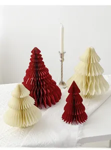 Detail of paper honeycomb Christmas trees in red and cream on a textured white tablecloth
