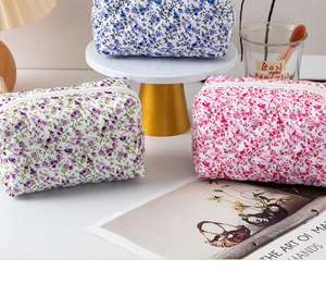 Detail view of three quilted floral cotton makeup bags with diamond stitching and zippers
