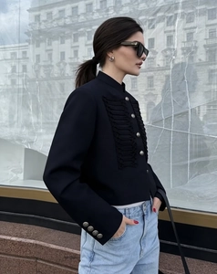 Detail of elegant black stand collar jacket with fringe and woven button design