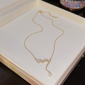 Detail of golden heart necklace featuring pearl charm and rhinestone inlay in a box