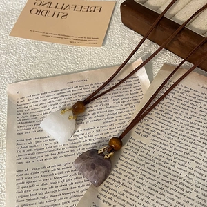 Detail of bohemian long necklaces featuring heart-shaped purple and white natural stone pendants