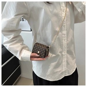 Close-up of brown patterned leather mini square bag with golden chain strap on model