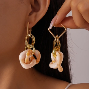 Close-up of geometric twisted resin earrings in milk tea color on a fashion model