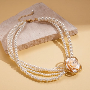 Detail of layered pearl necklace with pink camellia floral pendant and gold hardware