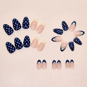 Detail of cream French almond press-on nails with blue dots, stars, and pearls