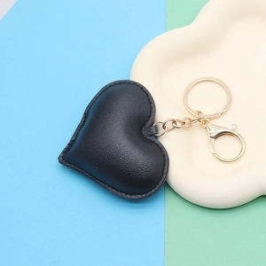 Detail of black heart-shaped leather keychain with lychee texture and golden lobster clasp