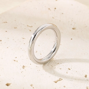Vertical view of a minimalist silver stainless steel ring on a textured stone surface
