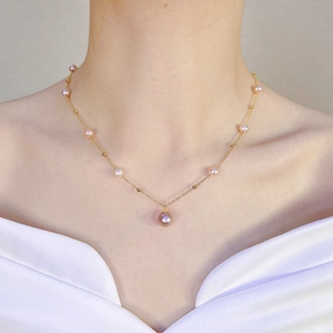 Close-up of pink freshwater pearl necklace with gold chain on model's neck