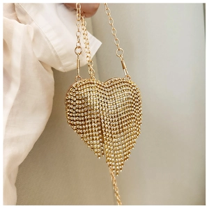 Detail of gold heart-shaped evening bag with shimmering rhinestones and tassel fringe