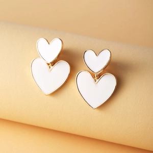 Macro view of double heart stud earrings with gold plating and white enamel finish